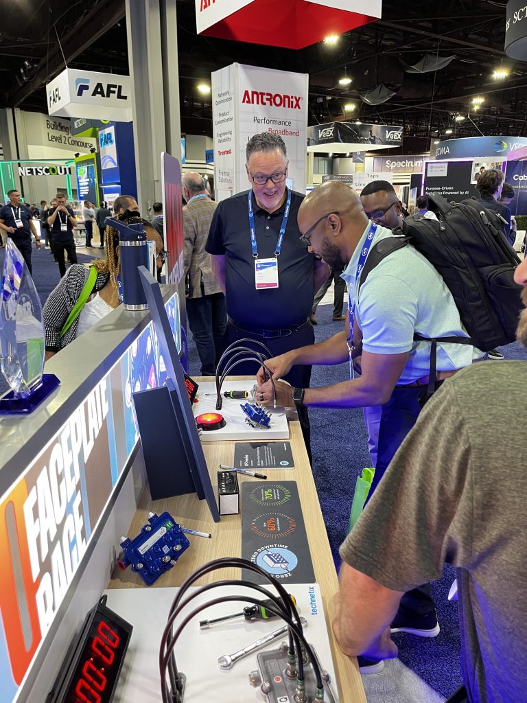 People interacting with demonstration displays on an exhibitor stand in a technology tradeshow environment. 